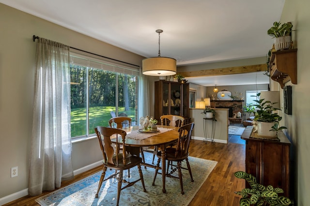 dining space with a brick fireplace and dark hardwood / wood-style floors