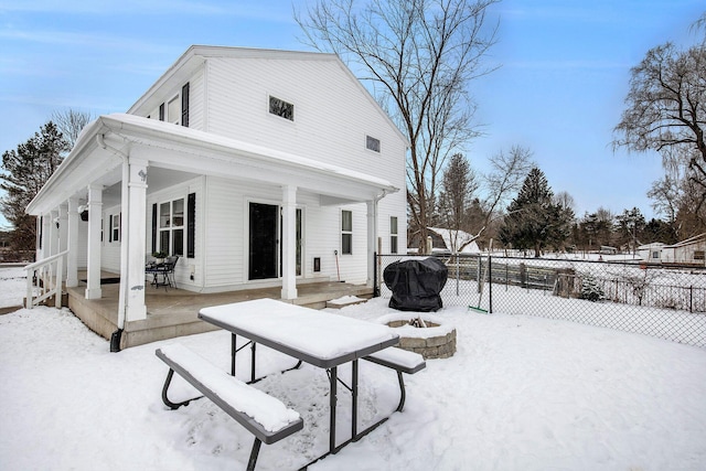 snow covered rear of property with an outdoor fire pit