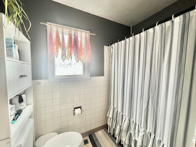 bathroom with tile walls, curtained shower, and toilet