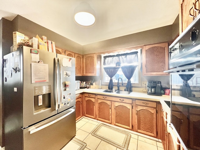 kitchen with sink, light tile patterned floors, stainless steel fridge, and black oven