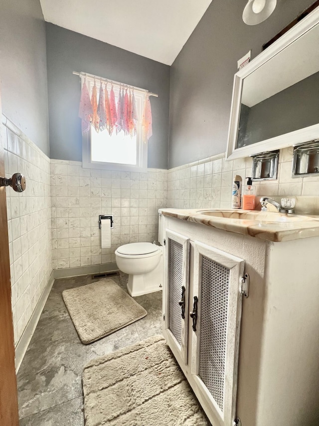 bathroom featuring tile walls, vanity, and toilet