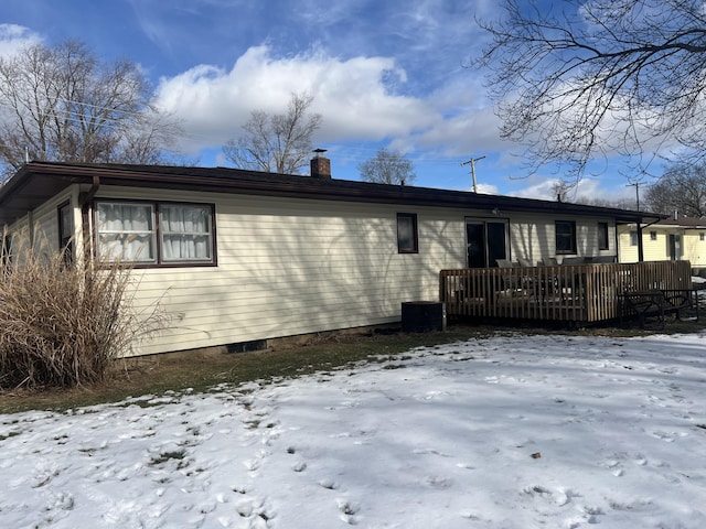 snow covered back of property with a deck