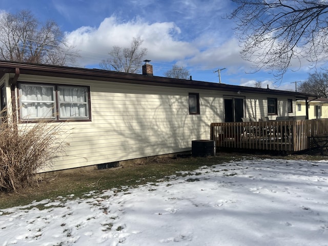 snow covered back of property featuring a wooden deck