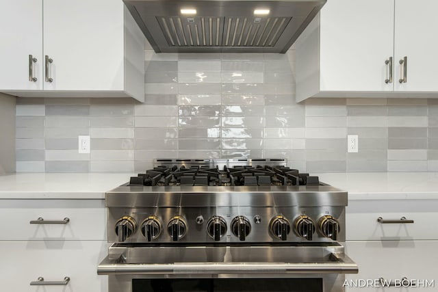 kitchen with white cabinetry, wall chimney range hood, light stone counters, and high end stove