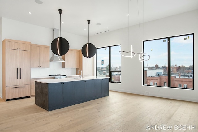 kitchen featuring hanging light fixtures, sink, a center island with sink, and light brown cabinets