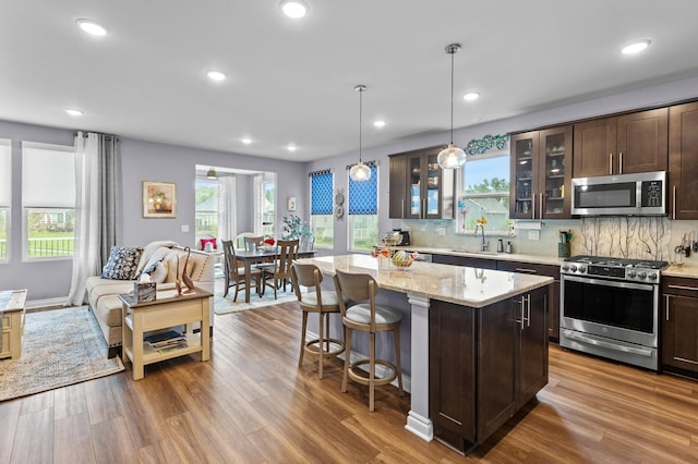 kitchen featuring dark brown cabinetry, stainless steel appliances, a kitchen island, and hanging light fixtures