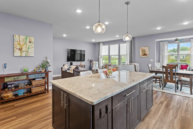 kitchen featuring a healthy amount of sunlight, decorative light fixtures, dark brown cabinets, and light hardwood / wood-style flooring