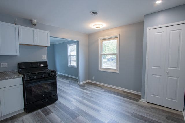 kitchen featuring hardwood / wood-style flooring, white cabinetry, and black gas stove