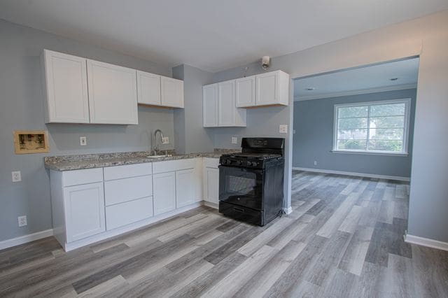 kitchen featuring white cabinetry, black gas stove, sink, and light wood-type flooring