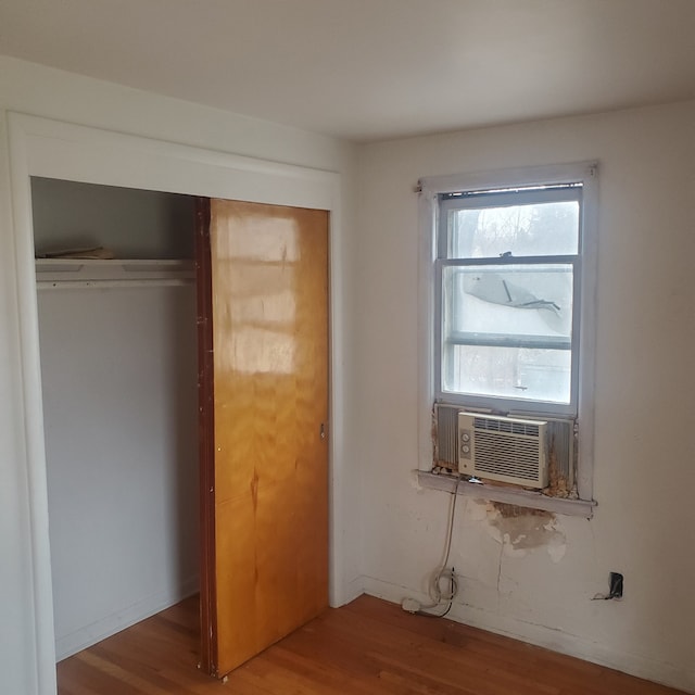 unfurnished bedroom with cooling unit, hardwood / wood-style floors, and a closet