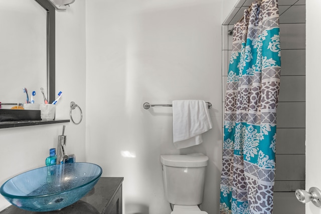 bathroom featuring vanity, walk in shower, and toilet