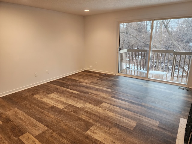 spare room featuring dark hardwood / wood-style flooring and a textured ceiling