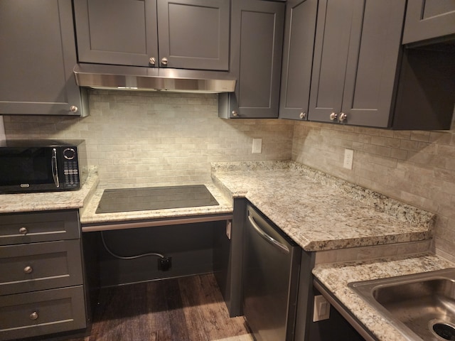 kitchen with dark wood-type flooring, gray cabinets, light stone counters, black appliances, and decorative backsplash