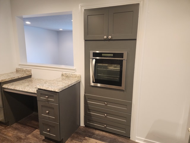 kitchen featuring light stone countertops, oven, and dark hardwood / wood-style flooring