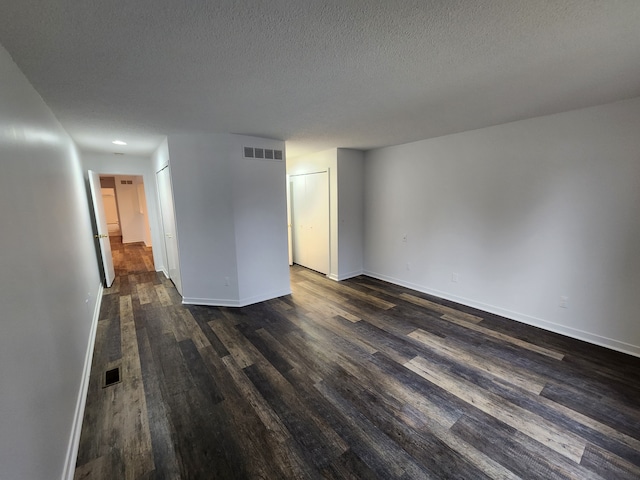 empty room with dark wood-type flooring and a textured ceiling