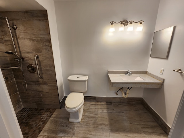 bathroom featuring a tile shower, sink, and toilet