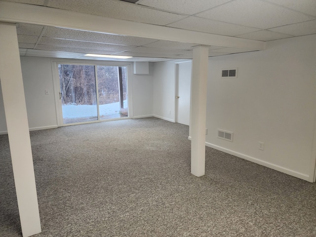 basement featuring a paneled ceiling and dark carpet