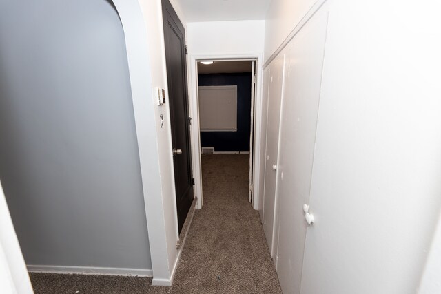 hallway featuring dark colored carpet