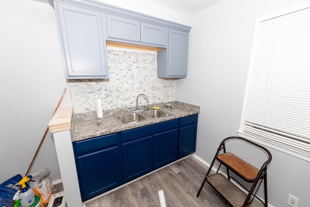 kitchen featuring dark hardwood / wood-style floors, sink, blue cabinetry, and decorative backsplash