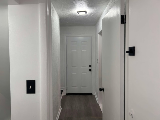 hall featuring dark wood-type flooring and a textured ceiling