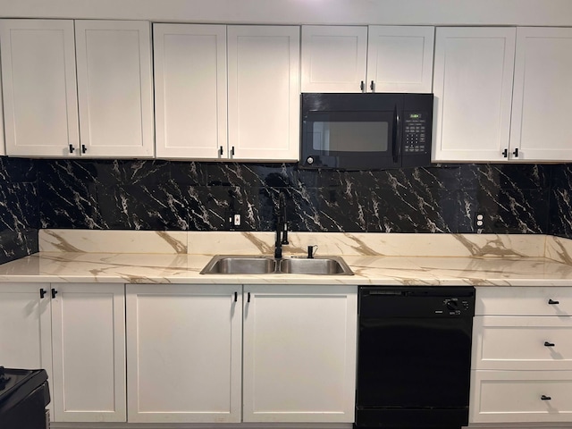 kitchen with tasteful backsplash, sink, white cabinets, black appliances, and light stone countertops