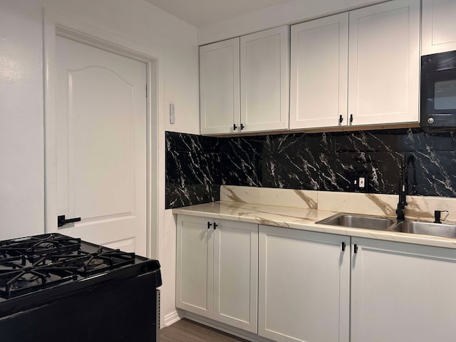 kitchen featuring sink, white cabinets, decorative backsplash, black appliances, and light stone countertops