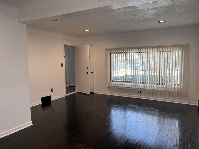 empty room with dark hardwood / wood-style floors and a textured ceiling