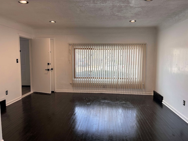 unfurnished room with dark wood-type flooring and a textured ceiling