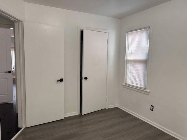 unfurnished bedroom with dark hardwood / wood-style floors and multiple windows