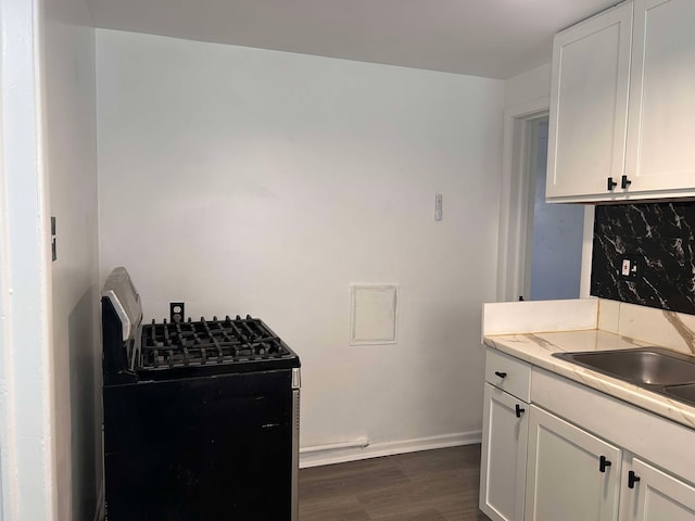 kitchen with white cabinetry, dark wood-type flooring, sink, and gas range