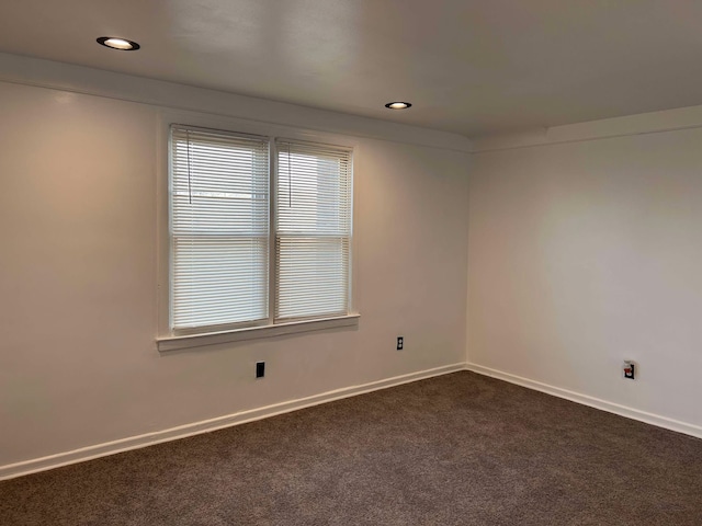 unfurnished room featuring dark colored carpet