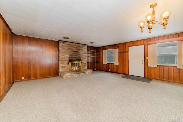 unfurnished living room featuring a stone fireplace, light carpet, and wood walls