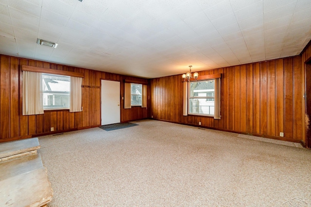 unfurnished living room with wooden walls and a chandelier