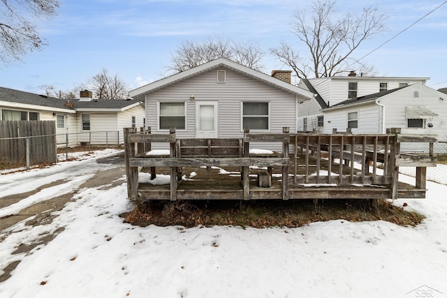 snow covered rear of property with a deck