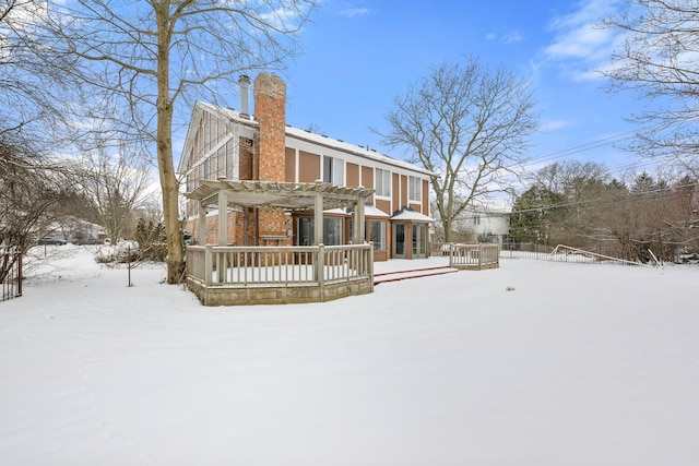 snow covered back of property with a pergola