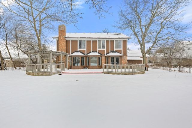 snow covered property with a wooden deck and a pergola