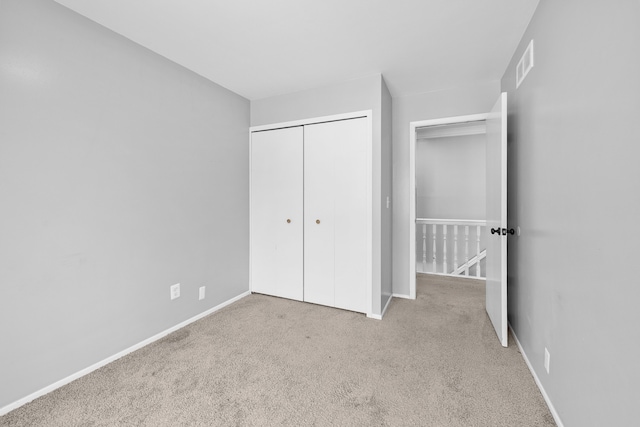 unfurnished bedroom featuring light carpet and a closet