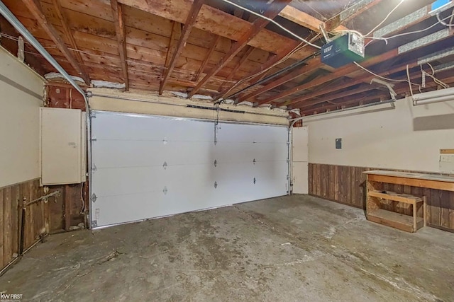 garage with a garage door opener, wooden walls, and electric panel