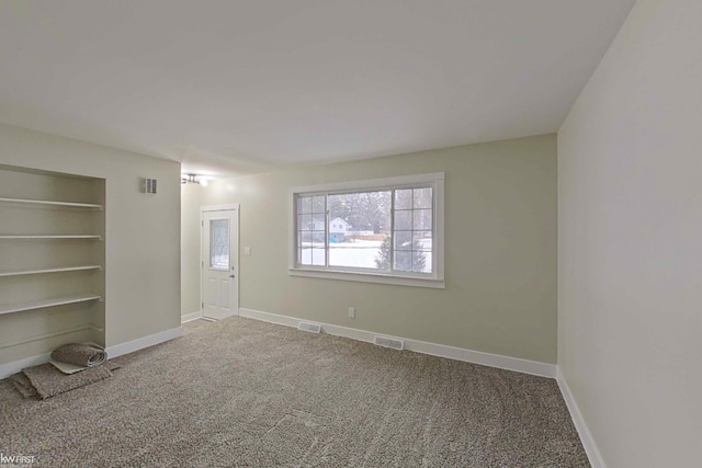 empty room with built in shelves and carpet floors