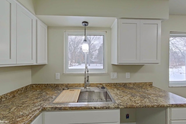 kitchen featuring hanging light fixtures, a healthy amount of sunlight, sink, and white cabinets