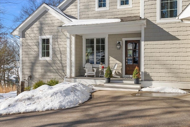 snow covered property entrance with covered porch