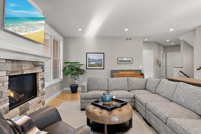 living room with a stone fireplace and light hardwood / wood-style floors