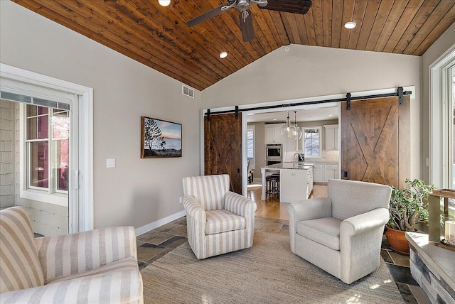 living room featuring lofted ceiling, wooden ceiling, a barn door, and ceiling fan