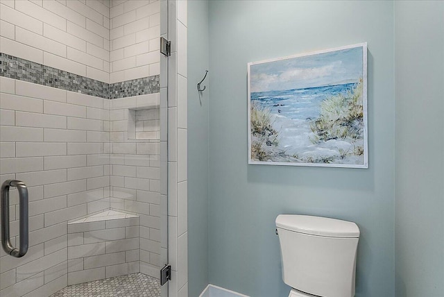 bathroom featuring a shower with shower door and toilet