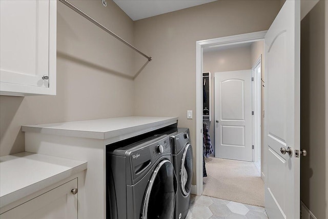 clothes washing area with independent washer and dryer, light colored carpet, and cabinets