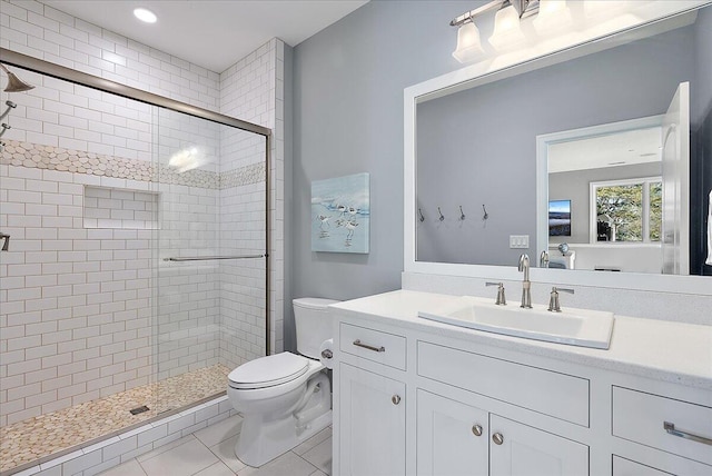 bathroom featuring vanity, a shower with shower door, tile patterned floors, and toilet