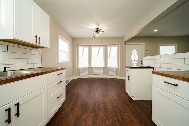 kitchen featuring white cabinetry, butcher block countertops, decorative backsplash, and dark hardwood / wood-style flooring