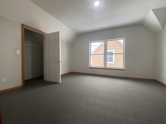 bonus room with lofted ceiling and dark colored carpet