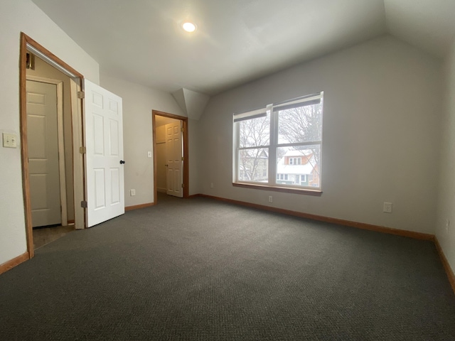 unfurnished bedroom featuring lofted ceiling and dark carpet