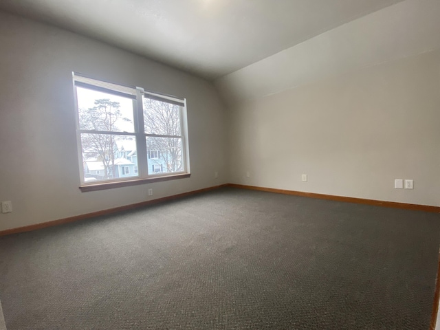 carpeted spare room featuring vaulted ceiling